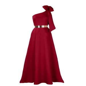 Detail view of the one-shoulder design with a large bow and gold belt on red dress