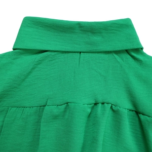Close-up of emerald green shirt collar with textured fabric and back pleat detail