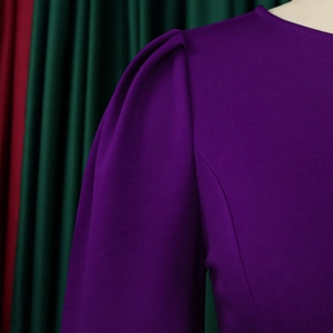 Detail of purple puff sleeves and curved stitching on high-quality knitted fabric