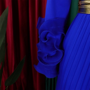 Détail d'une combinaison plissée bleu marine avec manches à volants et ceinture dorée