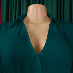 Detail of elegant dark green pleated dress featuring a deep V-neck and crisp collar design