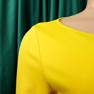 Detailed close-up of the round neckline and fabric texture on a yellow fashion dress