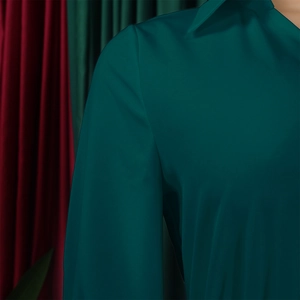 Detailed view of the dark green pleated dress neckline showing high quality refined texture