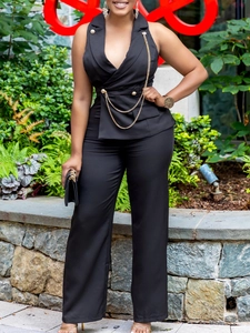 Women's black sleeveless blazer suit with gold chains and wide-leg trousers