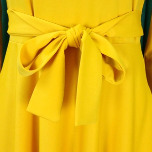 Detail of a ginger yellow long dress featuring a wide tied bow belt at the waist area