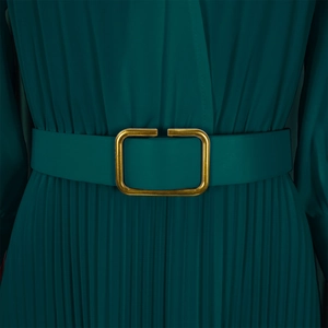 Detail of dark green pleated dress featuring a sleek waist belt with a matte gold buckle