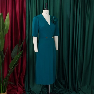 Detail of elegant V-neck dark green dress with gold buttons and 3D floral accent