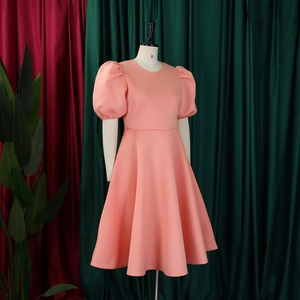 Détail d'une robe de soirée rose corail avec manches bouffantes et jupe trapèze à taille haute