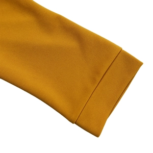 Détail de la manche jaune moutarde avec texture plissée et ourlet à double couture fine