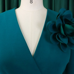 Detail of the oversized 3D flower decoration and elegant V-neck on a teal green dress