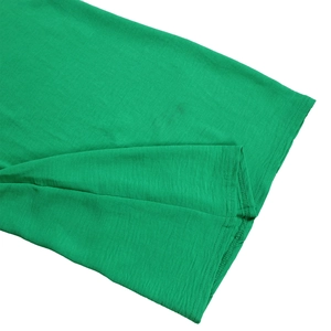 Detailed macro shot of double-needle stitching on green long-sleeve knit jumpsuit hem