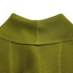Dettaglio macro del tessuto plissettato verde oliva e del collo a lupetto della blusa