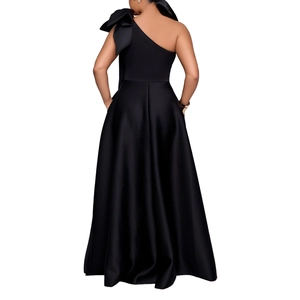 Macro view of a black one-shoulder satin evening dress featuring a large designer bow detail