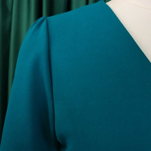 Detailed view of elegant V-neckline and puff sleeve texture on teal blue dress