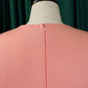 Détail du dos d'une robe de soirée rose montrant la fermeture éclair invisible et le col rond