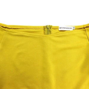Détail d'une combinaison jaune avec fermeture éclair invisible au dos et étiquette de marque