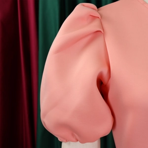 Gros plan sur les manches bouffantes roses montrant la texture du tissu structuré
