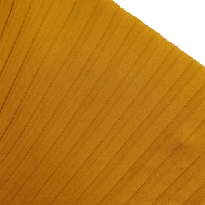 Gros plan sur le tissu plissé jaune gingembre avec texture verticale sur robe africaine