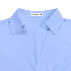 Detail of elegant V-neckline and woven brand label on light blue pleated dress fabric