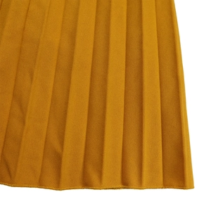 Détail de l'ourlet de la jupe plissée jaune gingembre avec texture et couture nette