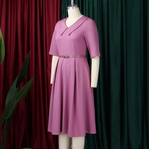 Dettaglio dell'abito color malva con scollo a V a revers e cintura con fibbia dorata