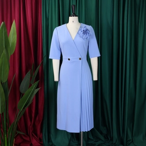 Detail of light blue V-neck dress featuring a 3D floral accent and pleated skirt