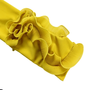 Détail de manches à volants superposés avec plis accordéon sur une combinaison jaune