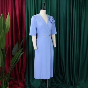 Detail of light blue V-neck dress featuring a 3D flower and gold buttons on waist