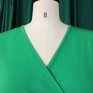 Detail view of a V-neckline on a grass green dress with fine weave and clean stitching