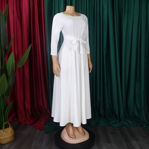 Detail of white long-sleeve maxi dress showing the tie-waist bow and elegant pleated hem