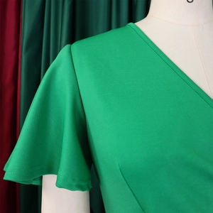 Detail of bright green V-neck dress with ruffle sleeves and textured fabric