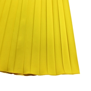 Détail du pantalon plissé jaune vif à jambes larges montrant les coutures et la texture