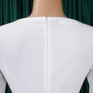 Detail of invisible back zipper closure on white long-sleeve dress with woven texture