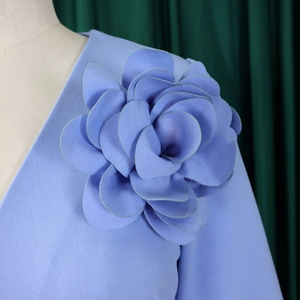 Detailed shot of large 3D fabric flower on shoulder of light blue chiffon dress