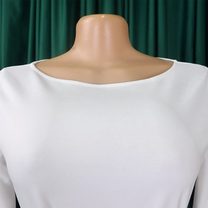 Close-up of the elegant boat neckline on a white solid color dress with ribbed texture