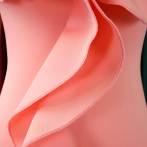 Close-up of pink dress showing elegant ruffle details and refined overlock stitching