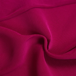 Primo piano del tessuto a pieghe rosso rosa scuro con costine verticali e lucentezza seta