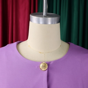Close-up of a purple round neck top with a vintage embossed gold button detail