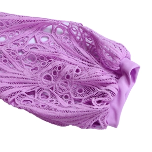 Close-up detail of purple hollow lace crochet patterns and textured fabric on the dress