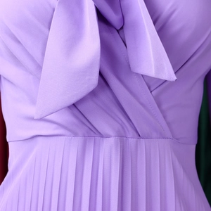 Detail of elegant purple pleated dress showing V-neckline with a delicate bow tie knot