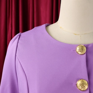 Detail of purple crew neck top with puff sleeves and gold relief buttons on the shoulder