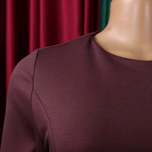 Close-up of elegant maroon crew neck and shoulder stitching on textured knit dress
