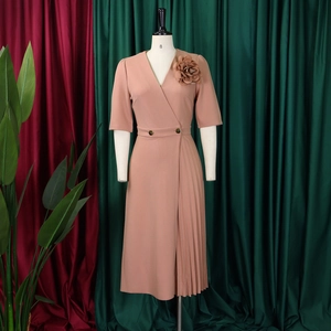 Detailed view of 3D floral accent and elegant pleated hem on a dusty pink V-neck dress