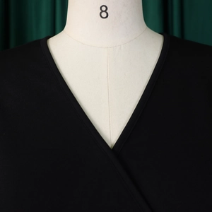 Close-up of the crossover V-neck detail and twill fabric texture on a black dress