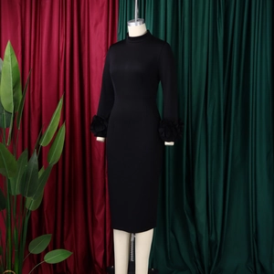 Close-up of elegant black pencil dress featuring a large 3D floral accent on the long sleeve
