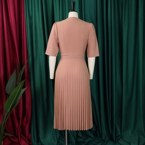 Detail of the pink V-neck pleated dress featuring short sleeves and a matching waist belt