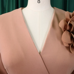 Detail of elegant V-neckline with 3D floral applique on pink pleated dress fabric