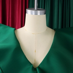 Detailed view of the V-neckline and glossy satin fabric of this dark green fishtail dress