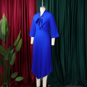 Close-up of royal blue pleated dress featuring a bow tie neckline and 3/4 flare sleeves
