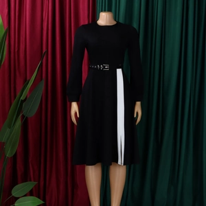 Detail of elegant black long-sleeve dress featuring a white contrast panel and side slit